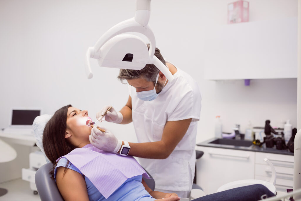 Dentist examining female patient teeth in clinic image